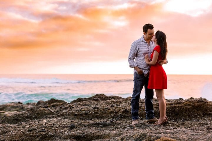 Couple looking at each other lovingly with an epic sunset behind them at their Laguna Beach engagement session